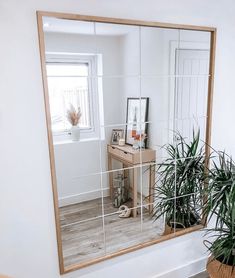 a mirror that is on top of a wooden table next to a potted plant