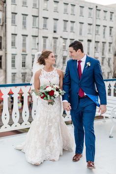 a bride and groom holding hands walking down the street