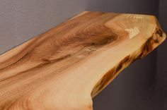 a close up of a wooden table with grey walls in the background and wood grain on the edge