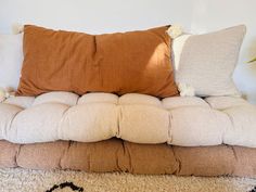 a couch with two pillows on it and a plant in the corner next to it