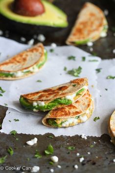 two quesadillas stacked on top of each other next to an avocado