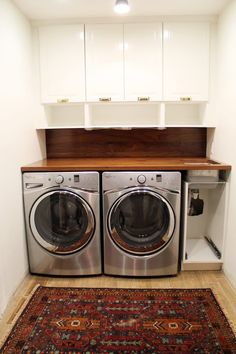 a washer and dryer in a small room with an area rug on the floor