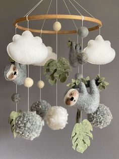 a stuffed slotty hanging from a mobile with balls and leaves in the shape of clouds