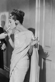 an old photo of a woman brushing her teeth with a man standing next to her