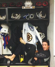 a man sitting on top of a bench next to a locker filled with hockey gear