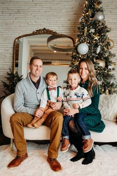 a family sitting on a couch in front of a christmas tree