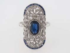 Vintage Filigree Cocktail Ring Art Deco Sapphire in Platinum $5,250.00 Vintage Filigree Cocktail Ring Art Deco Sapphire in Platinum. The center oval sapphire is approximately 1.20 carats and is a slightly darker royal blue with medium transparency. The platinum open filigree is set with rose cut diamonds. The border of this unique Art Deco oval shaped cocktail ring is set with french cut sapphires creating a frame around this lovely ring. Composition: Platinum Ring Size: 6.75 Center Stone Shape: Edwardian Ring, Vintage Cocktail Ring, Asscher Cut Diamond, Swirl Ring, Fine Ring, Sapphire Wedding, Right Hand Rings, Ring Art Deco, Deco Jewelry