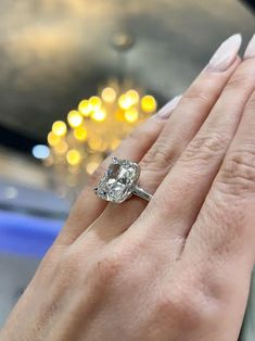 a close up of a person's hand with a diamond ring on their finger