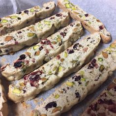 several pieces of bread with nuts and dried fruit on them sitting on a piece of parchment paper