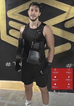 a man standing in front of a black and gold wall with his hands on his hips