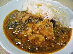 a white plate topped with meat and vegetables covered in gravy next to rice