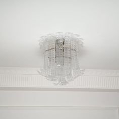 a chandelier hanging from the ceiling in a room with white walls and trim