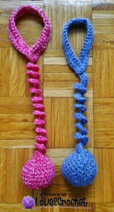 two crocheted toys are on the floor next to each other, one is pink and one is blue