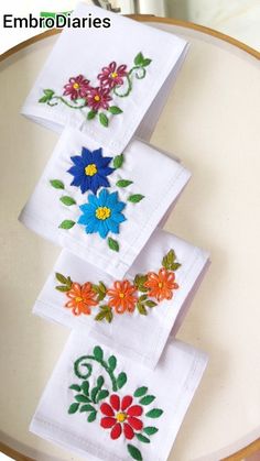 three embroidered napkins with flowers on them