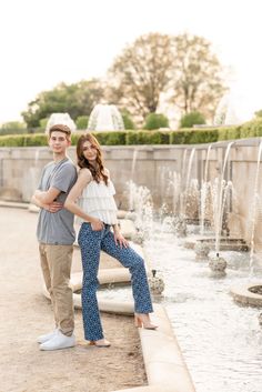 a man and woman standing next to each other in front of a fountain