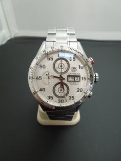 "For Sale: b893 Stylish Men's Automatic Tag Heuer Carrera Calibre 16 Wristwatch PLEASE READ ENTIRE DESCRIPTION BEFORE PURCHASING Please see pictures for more details! This nice watch is sure to please that special man in your life. It has a stainless steel case and bracelet band. Fixed bezel has the tachymetre markings. White dial has luminous silver tone hands and Arabic numerals. Analog dial contains 3 sub dials; 60 seconds, 30 minutes and 12 hours. Day of the week and date are displayed at th Tag Heuer Carrera Automatic, Baby Gold Rings, Nice Watch, Bulova Accutron, Tag Heuer Carrera Calibre, Heuer Carrera, Tag Heuer Carrera, Number 7, Filigree Ring