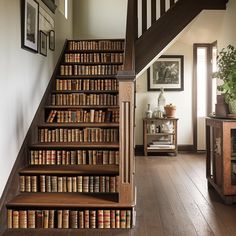 a staircase with bookshelves and pictures on the wall next to wooden flooring