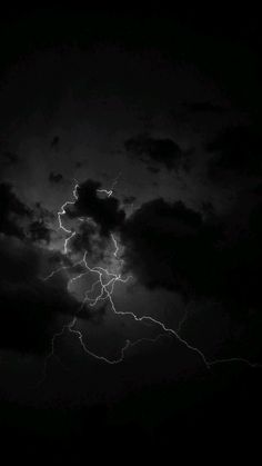 a black and white photo of lightning in the night sky with clouds, dark background