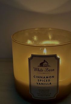 a candle that is sitting in front of a glass bowl with cinnamon spiced vanilla on it