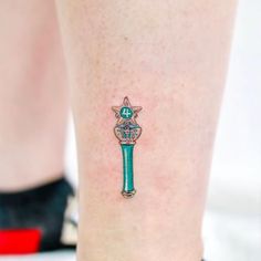 a small tattoo on the leg of a woman with a green pen and cross in it