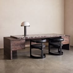 a desk with two stools and a lamp on top of it in an empty room