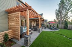 an outdoor patio with wooden pergoline and seating area on the side of it