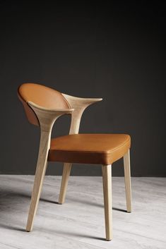 a wooden chair sitting on top of a white floor next to a black wall in an empty room