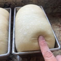 two loafs of bread sitting in pans on top of a counter next to each other