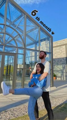 a man holding a woman in front of a glass building with the words 6 north on it