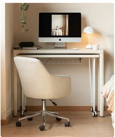 a computer monitor sitting on top of a desk next to a white chair and lamp