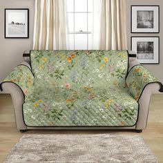 a living room with a couch covered in a green floral print cover next to pictures on the wall