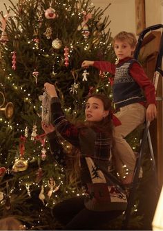 a young boy and girl standing in front of a christmas tree