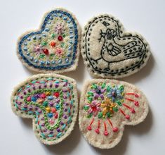 four embroidered heart shaped brooches on a white surface