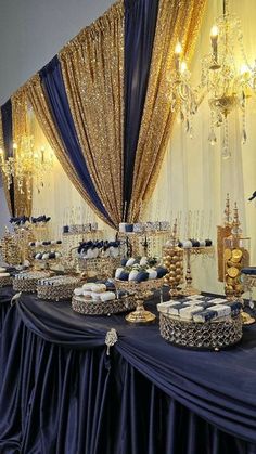 a table topped with lots of food covered in blue and gold cloths next to a chandelier