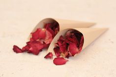 two white cones filled with red flowers on top of a table