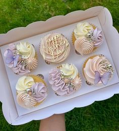 a box filled with cupcakes sitting on top of a lush green field