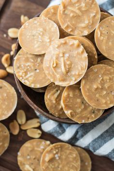 peanut butter cookies in a wooden bowl on a striped towel with almonds around them