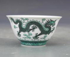 a green and white dragon bowl sitting on top of a gray countertop next to a wall