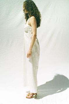 a woman standing in front of a white backdrop with her back to the camera looking down