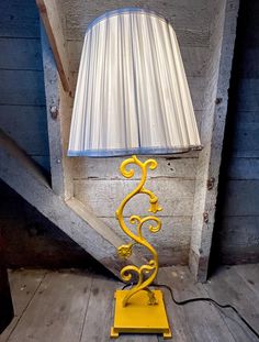 a yellow lamp sitting on top of a wooden floor next to a white shade light