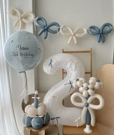 balloons and decorations are arranged on the table for a first birthday party in blue and white