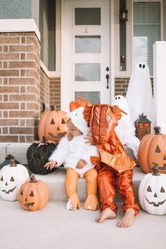 two children dressed up in halloween costumes sitting on the front steps