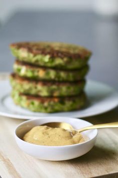 a stack of pancakes sitting on top of a table next to a bowl of sauce