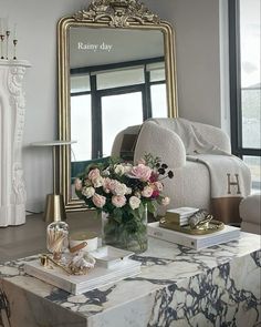 a living room with a large mirror and flowers in a vase on the coffee table