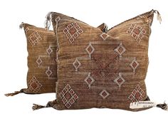 two decorative pillows with tassels on the sides, one brown and one tan