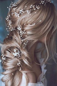 a woman with long blonde hair wearing a flowered headpiece and pearls in her hair