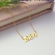 Introducing our Custom Year Necklace, the perfect personalized piece to commemorate a special date or milestone in your life! Handcrafted with love and attention to detail, this necklace features a delicate chain and a dainty pendant engraved with the year of your choice. Whether it's a birth year, anniversary, or any significant event, this necklace is a timeless keepsake to cherish for years to come. Treat yourself or surprise a loved one with a thoughtful and unique gift that will be treasure Year Necklace, Date Necklace, Number Necklace, Dainty Pendant, Birth Year, Lucky Number, Delicate Chain, Nouvel An, Perfect Gift For Her