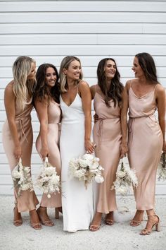 the bridesmaids are all dressed in different styles and colors, posing for a photo