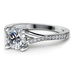 a white gold engagement ring with diamonds on the band and a round cut diamond in the center