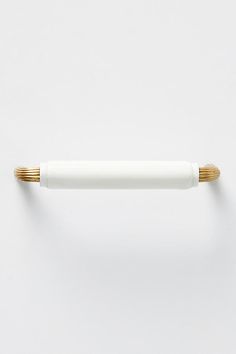 a white and gold pen on a white surface with one end pointing up at the camera